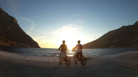 Twee mensen aan het water met de fiets in Sifnos