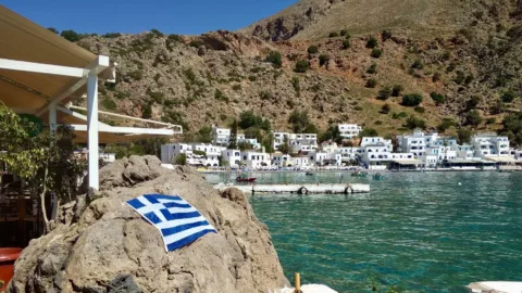 De griekse vlag op een rots bij Loutro